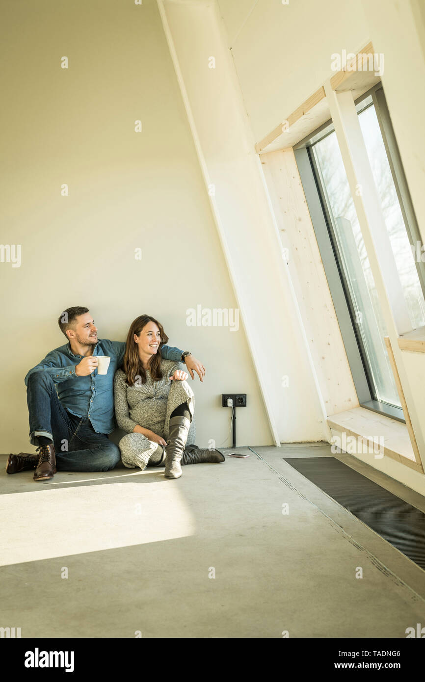 Heureux couple, attend baby sittig, sur le plancher de leur nouvel appartement Banque D'Images