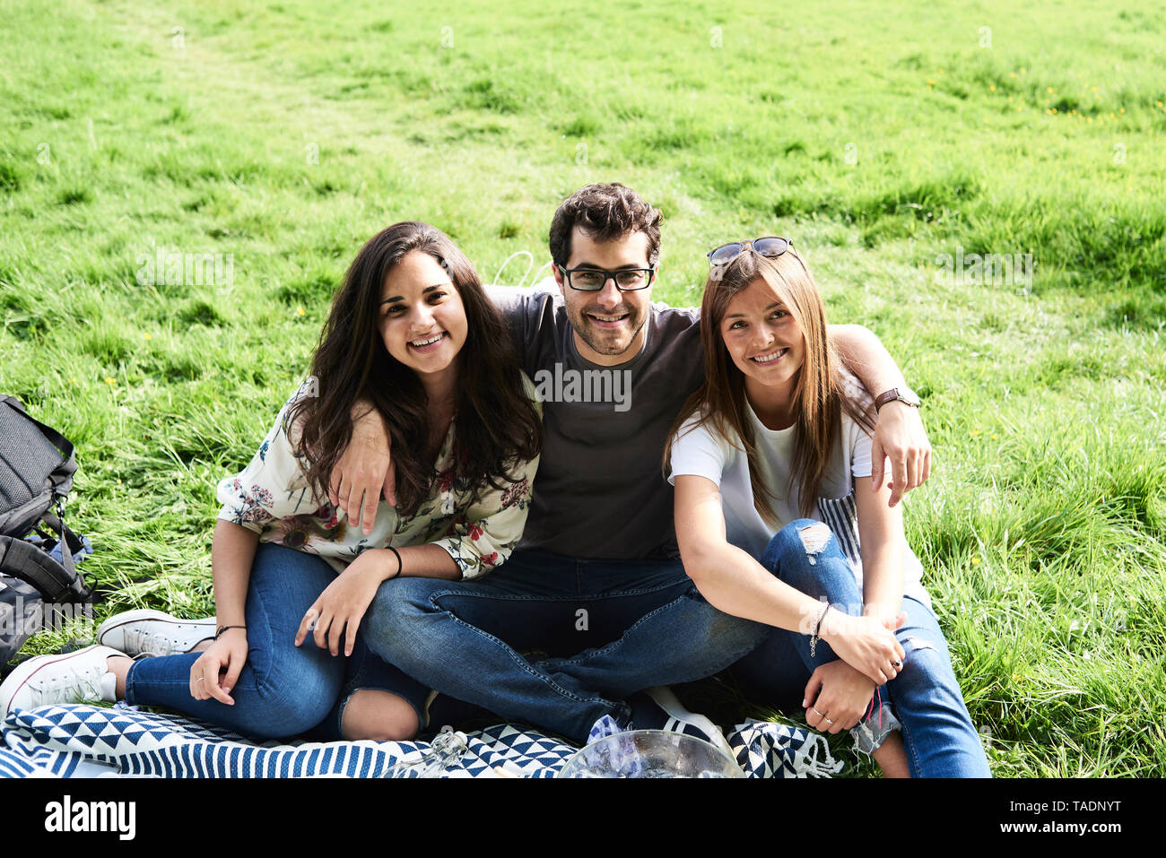Portrait of smiling friends sitting on a blanket in park Banque D'Images