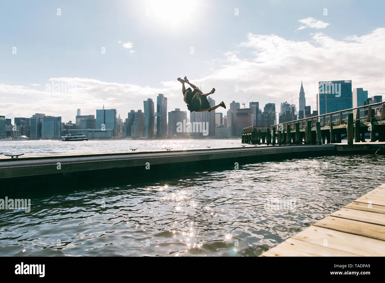 USA, New York, Brooklyn, deux jeunes hommes faisant backflip sur la jetée en face de Manhattan skyline Banque D'Images