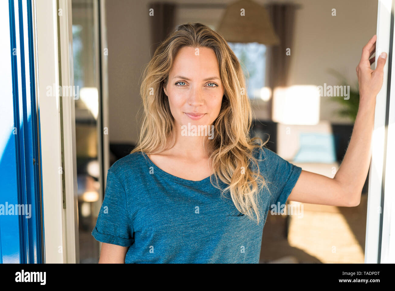 Portrait of smiling woman leaning à fenêtre ouverte à la maison Banque D'Images