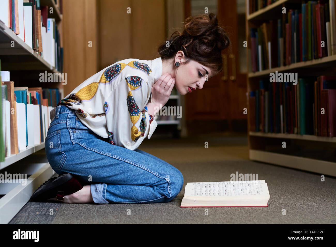 Female student reading book dans une bibliothèque publique Banque D'Images
