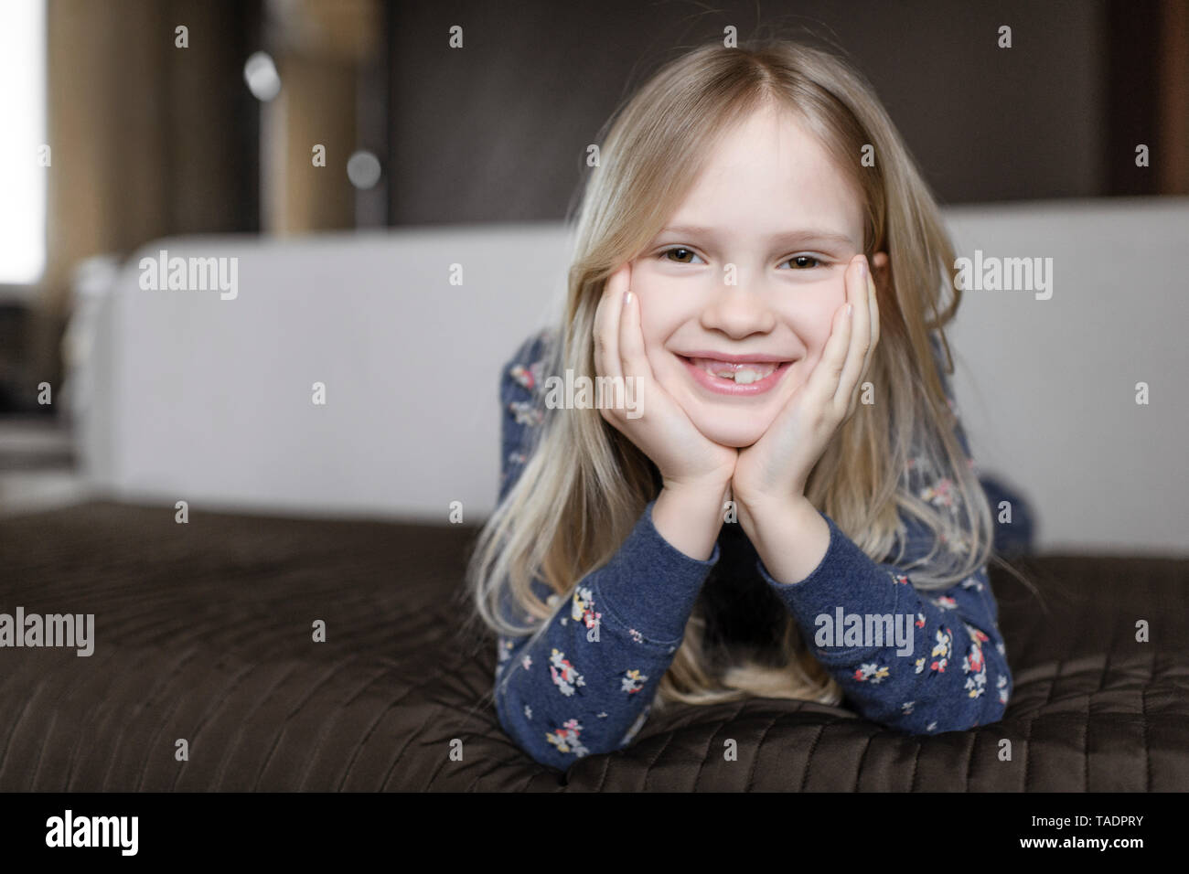 Portrait of smiling little girl avec écart de dent et la tête dans les mains Banque D'Images