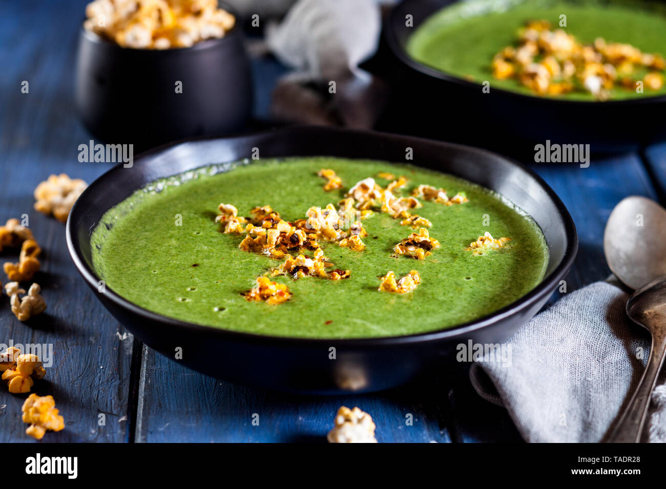 Soupe de légumes verts vegan aux épinards, poireaux et petits pois, maïs soufflé de chili Banque D'Images