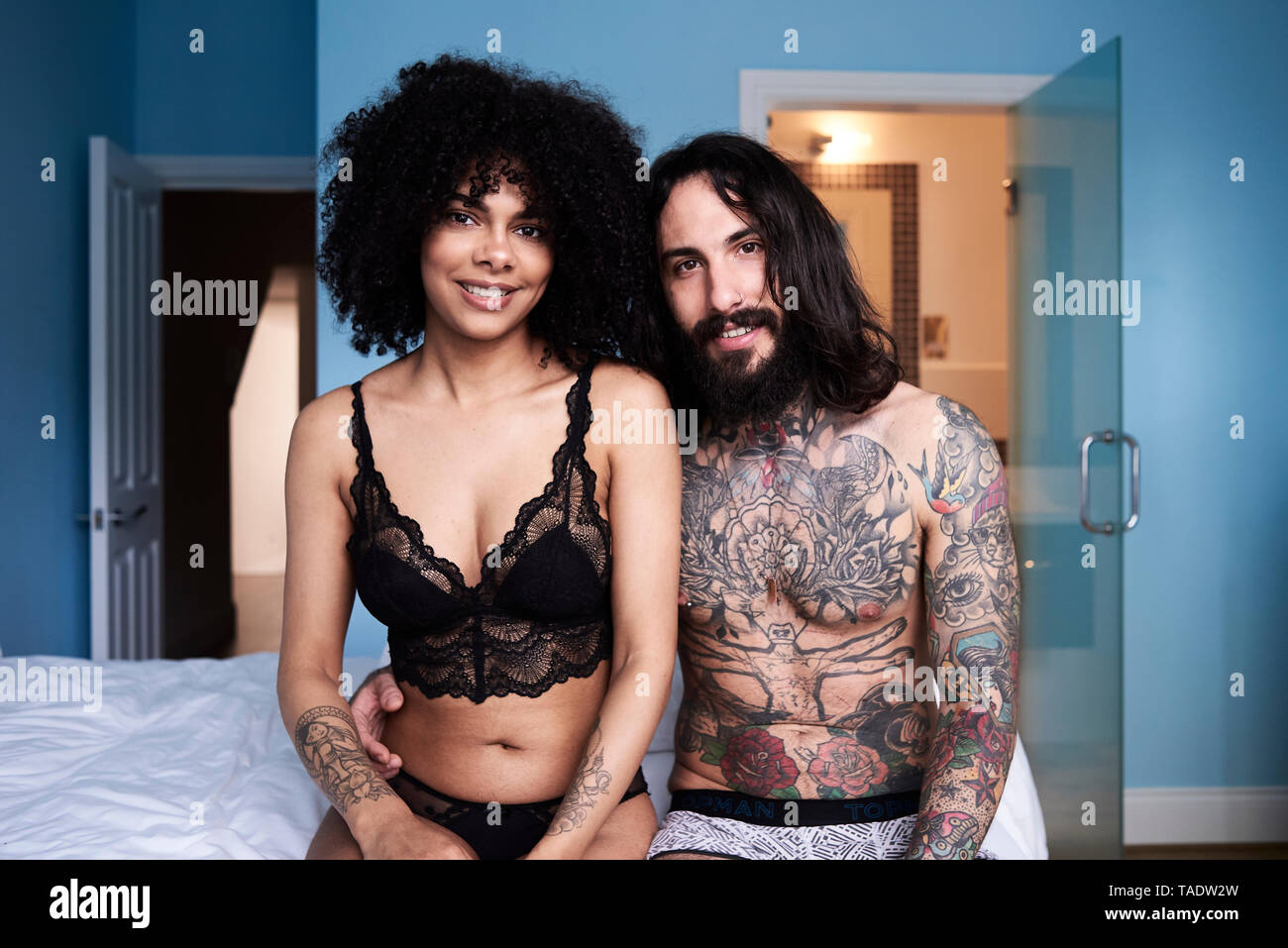 Portrait of smiling young couple sitting on bed Banque D'Images