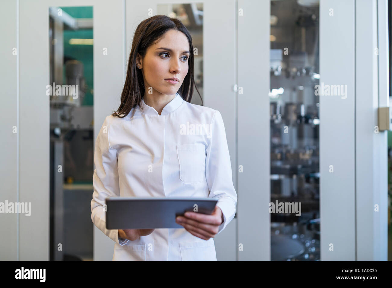 Woman with tablet portant manteau de laboratoire dans l'usine moderne Banque D'Images