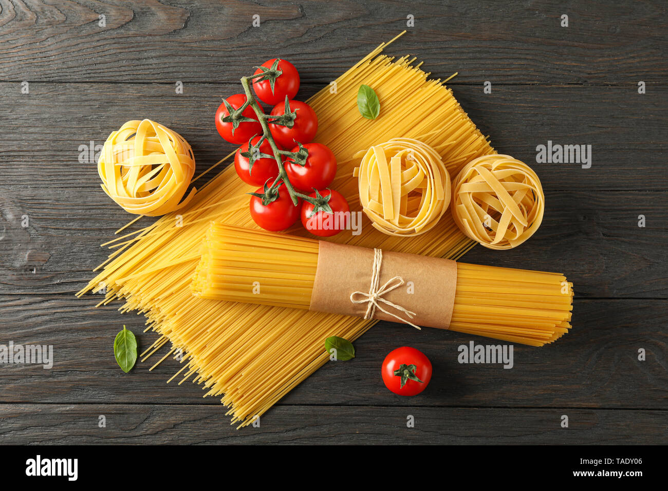 Composition avec des pâtes, des tomates et basilic sur fond de bois, de l'espace pour le texte et Vue de dessus Banque D'Images