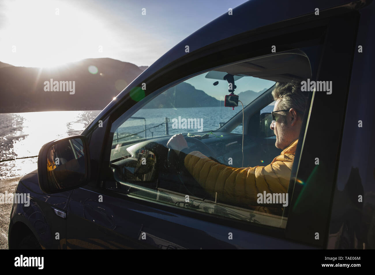 L'Italie, Como, man sitting in car en traversant le lac sur le ferry Banque D'Images L'Italie, Como, man sitting in car en traversant le lac sur le ferry Banque D'Images