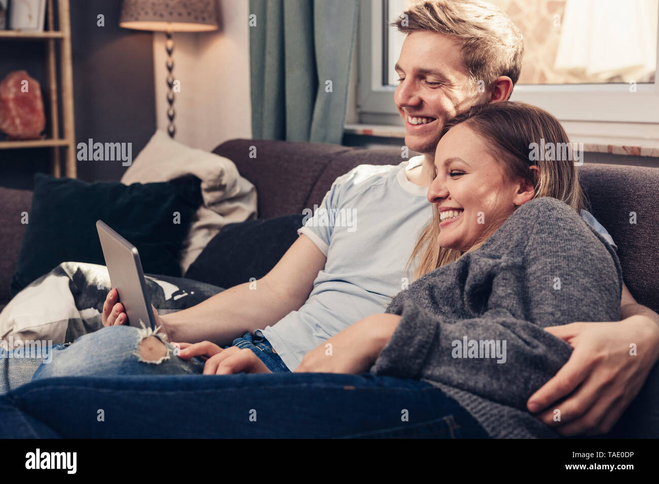 Happy young couple using tablet sur la table à la maison Banque D'Images