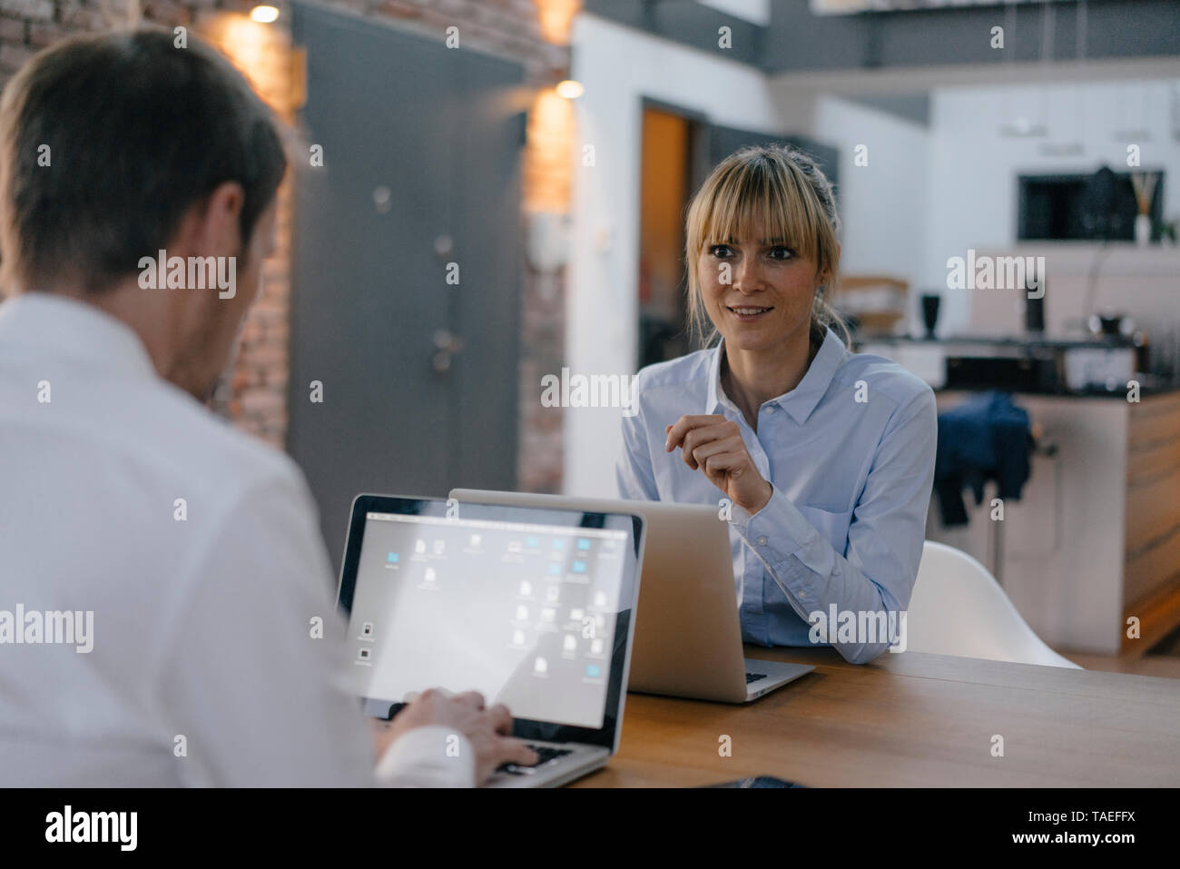 Businessman and woman sitting at desk, working on laptop Banque D'Images