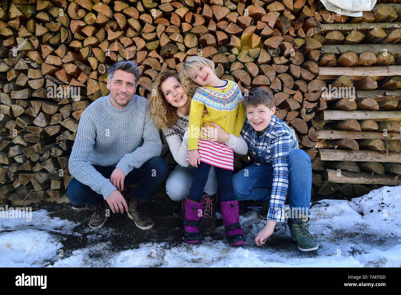 Portrait de famille heureuse en face de pile de bois en hiver Banque D'Images