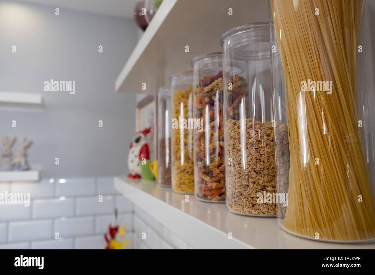 Divers produits alimentaires non cuites dans des bocaux en verre disposées sur des étagères blanches ar la cuisine Banque D'Images