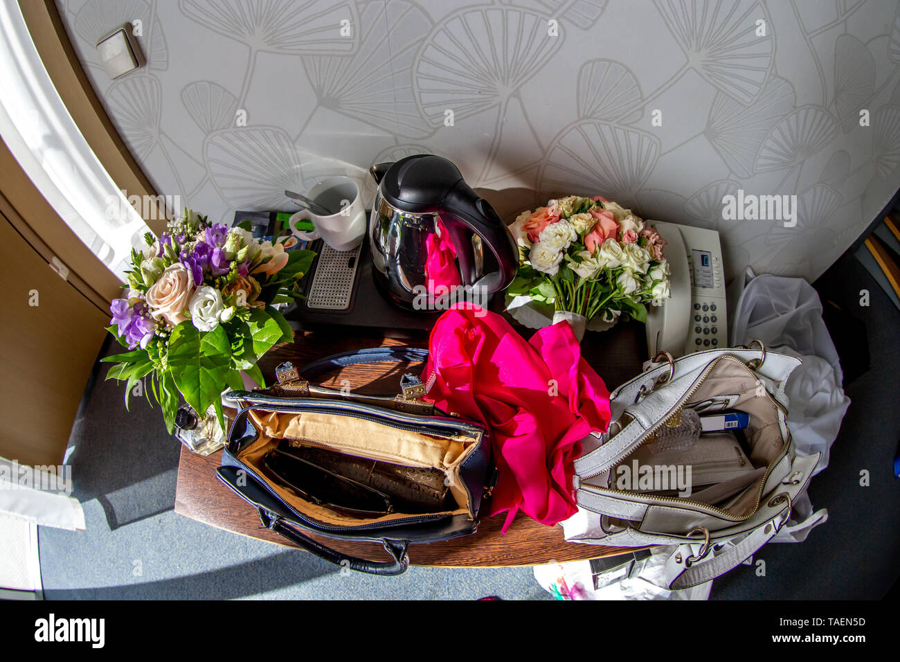 Les choses d'ouvrir lady sac. Théière, tasse à café, téléphone, foulard rouge, sacs, bouquets de fleurs et autres produits de beauté et des accessoires sur table de noce Banque D'Images