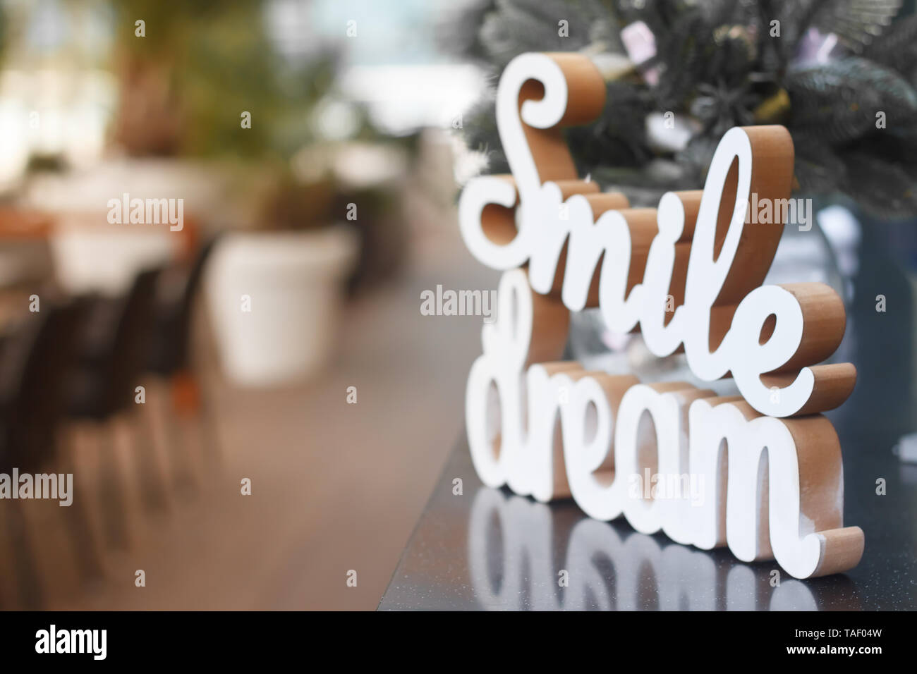 Gros plan du sourire et rêve mots en bois sur une surface de verre sur la table de fête, selective focus Banque D'Images