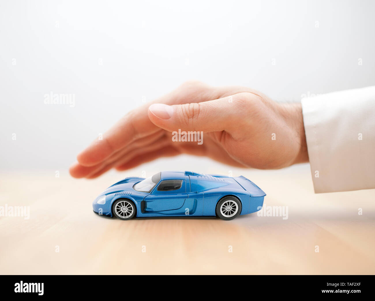 Assurance voiture concept avec voiture bleue à la main couverte de jouets Banque D'Images