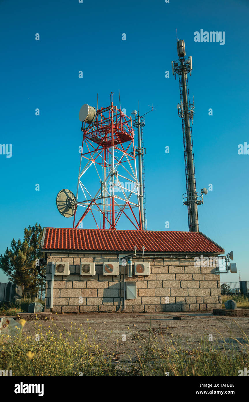 Les tours de télécommunication avec les antennes d'une station de base transceiver, sur le coucher du soleil à Guarda. Une ville médiévale à l'est du Portugal. Banque D'Images