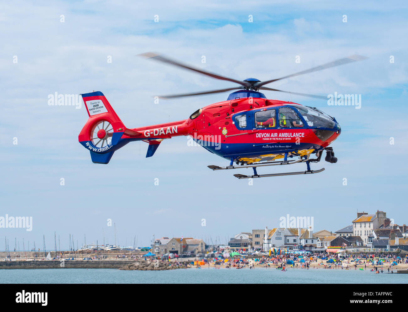 Lyme Regis, dans le Dorset, UK. 25 mai 2019. Devon Air Ambulance hélicoptère atterrit sur la plage bondée à Lyme Regis. L'hélicoptère décolle de la plage bondée avec un patient à bord. Credit : Celia McMahon/Alamy Live News. Banque D'Images