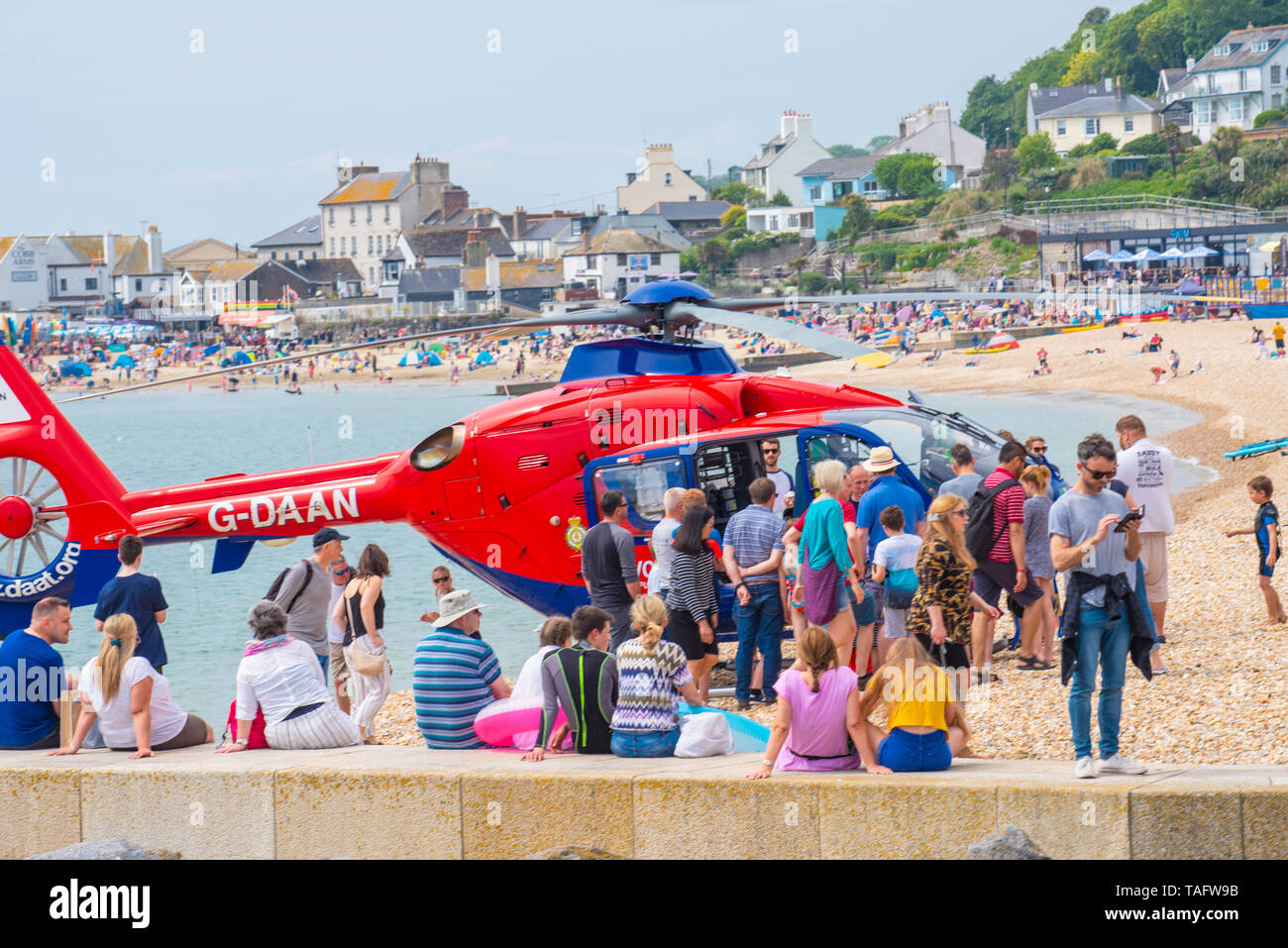 Lyme Regis, dans le Dorset, UK. 25 mai 2019. Météo France : des foules de touristes et visiteurs affluent à la plage de Lyme Regis pour se prélasser au soleil chaud. L'ambulance aérienne par hélicoptère Devon produit de l'intérêt chez les spectateurs comme il s'occupe d'une urgence sur la plage animée. Credit : Celia McMahon/Alamy Live News. Credit : Celia McMahon/Alamy Live News Banque D'Images