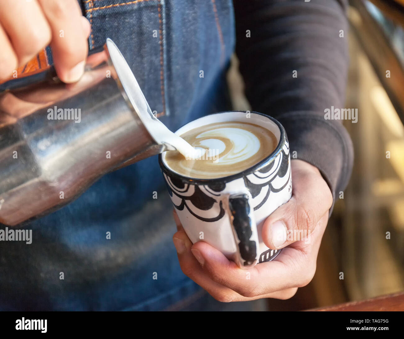 Un barista professionnel verse de la tulipe en mousse de latte sur du café, de l'espresso et crée un cappuccino parfait. Photo Banque D'Images