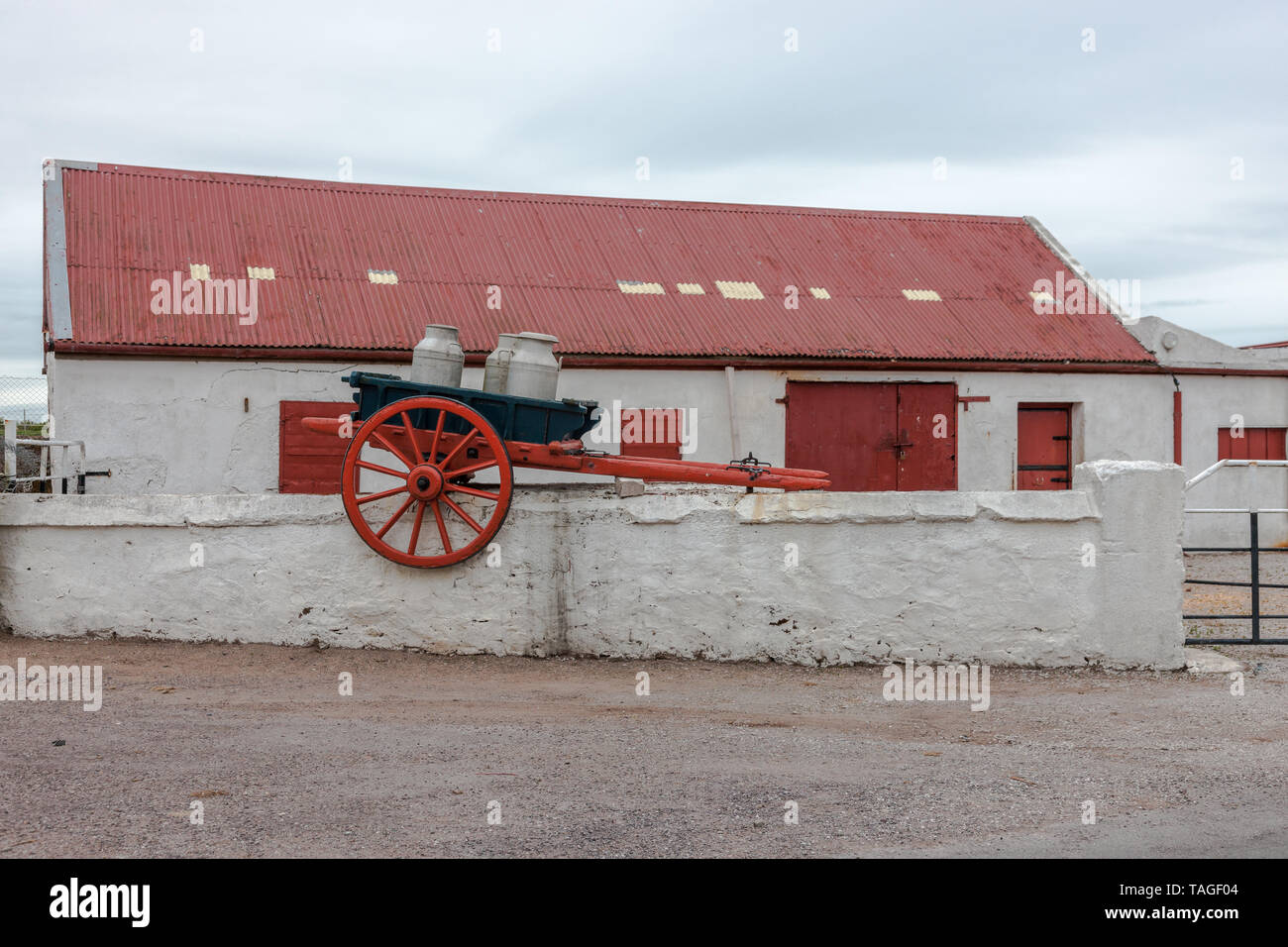Knockadoon, Cork, Irlande. Un panier vintage avec des bidons de lait qui est maintenant utilisé comme décoration, est assis sur un mur de ferme près de Knockadoon, Ireal Banque D'Images