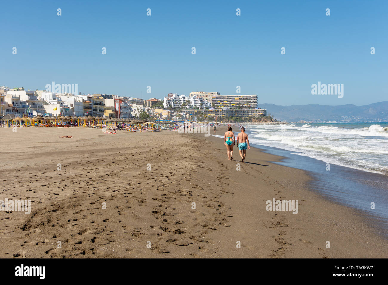 Couple en train de marcher le long de la plage à La Carihuela, Torremolinos, Costa del Sol, Espagne Banque D'Images