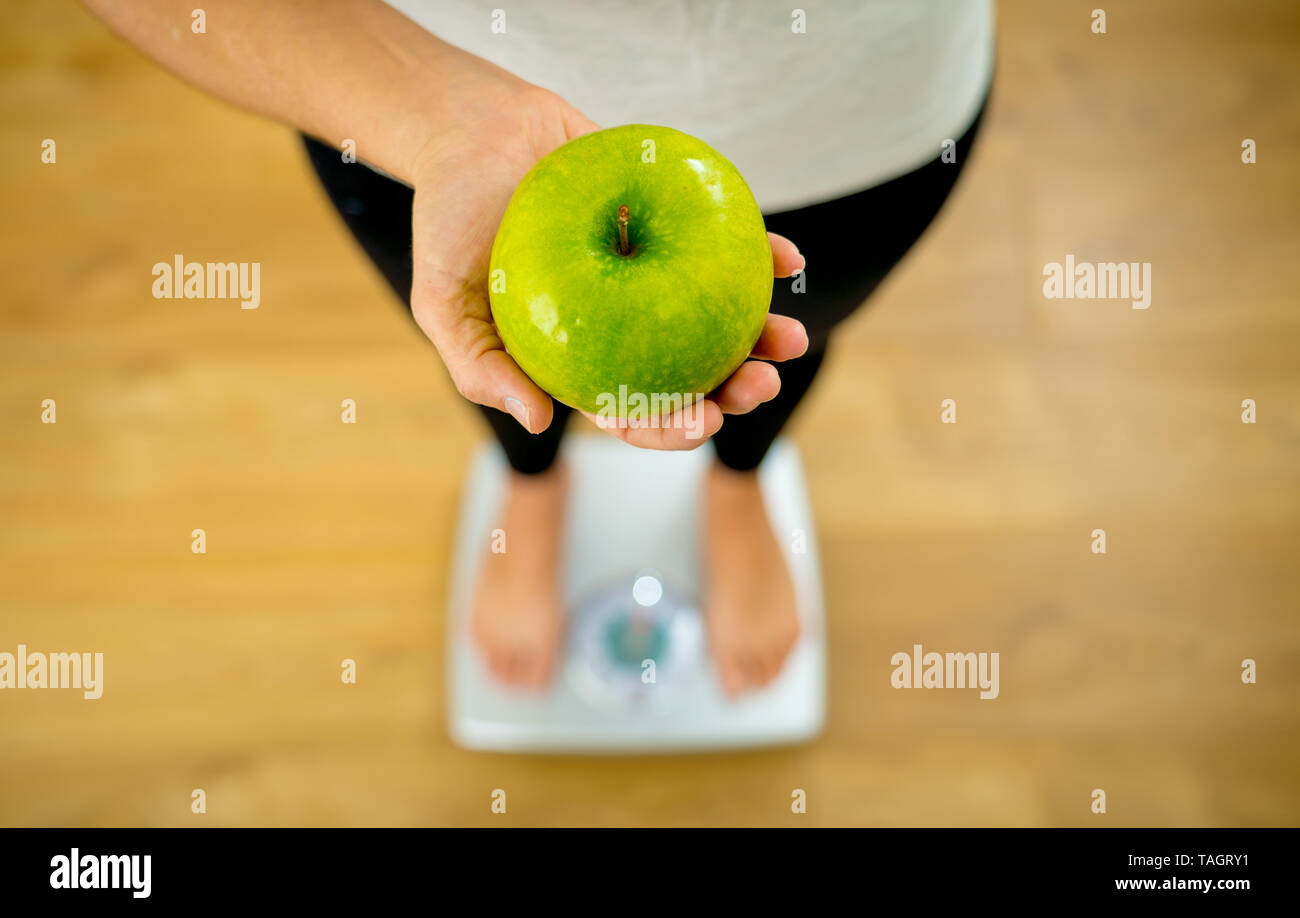 Close up of woman sur échelle holding fresh fruit pomme verte en main professionnels de la perte de poids et les habitudes alimentaires des aliments sains dans la Nutrition D Banque D'Images