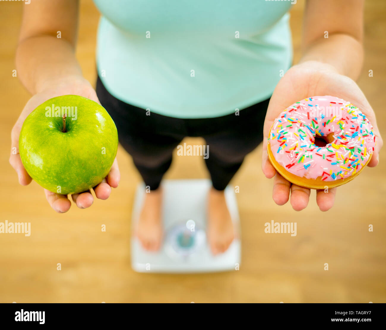 Close up of woman holding sur échelle sur les mains et faire des choix d'apple de beignes entre la santé des aliments malsains dessert pendant la mesure de poids de corps dans l'écrou Banque D'Images