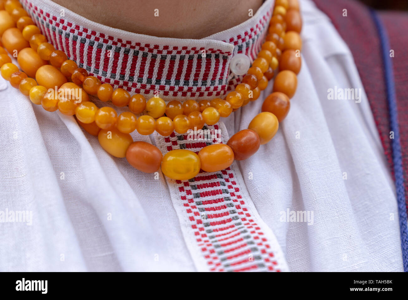Fragment d'une femme lituanienne costume national. L'Amber Collier fait de détails ronde sur la chemise de lin blanc motif tissé avec Banque D'Images