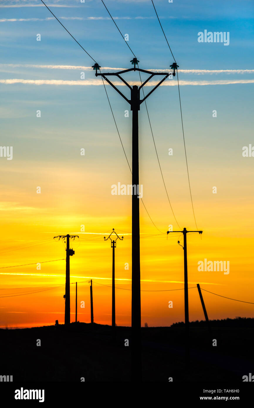 Lever du soleil derrière les poteaux d'électricité - France Banque D'Images
