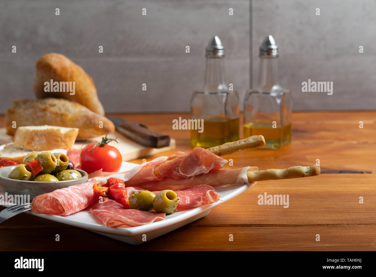 L'antipasto platter une viande froide plaque avec prosciutto, tranche de jambon, salami, décoré d'olives noires, tomates séchées et poivrons sur un sol en bois backgroun Banque D'Images