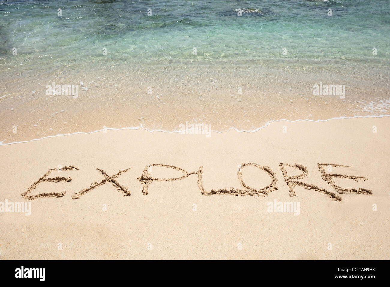 Close-up of Explorer Texte écrit sur le sable près de la mer à la plage Banque D'Images