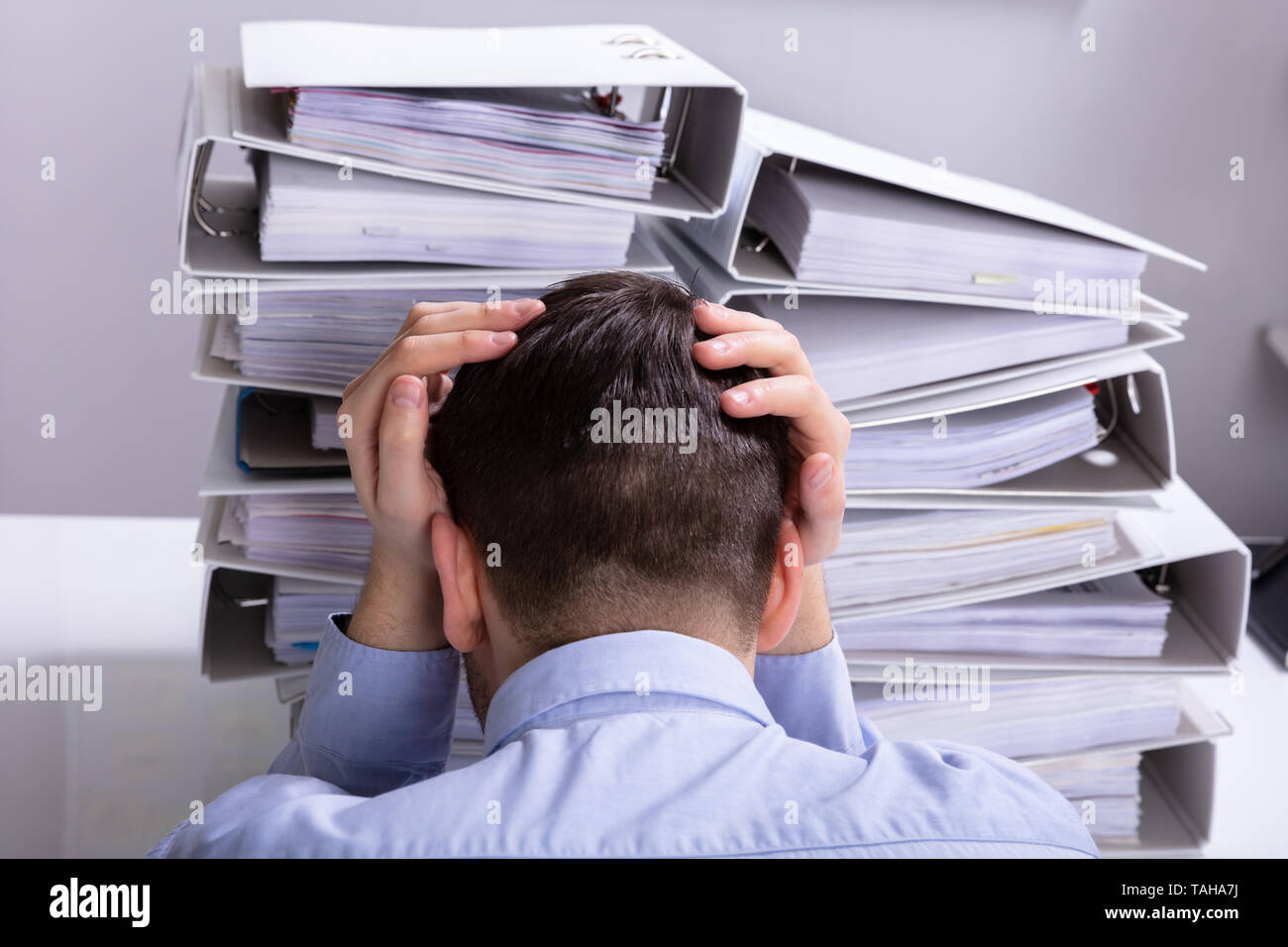 Vue arrière du souligné Businesswoman Pointing en face de dossiers empilés Banque D'Images