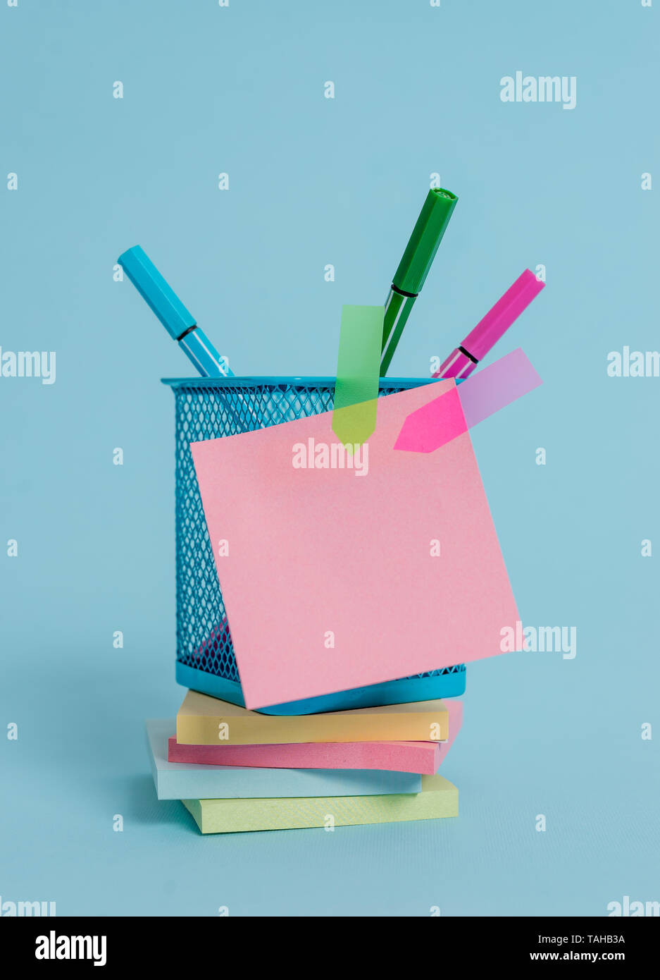 Sticky note pads empilés bannières flèche porte-stylos en métal fond pastel Banque D'Images