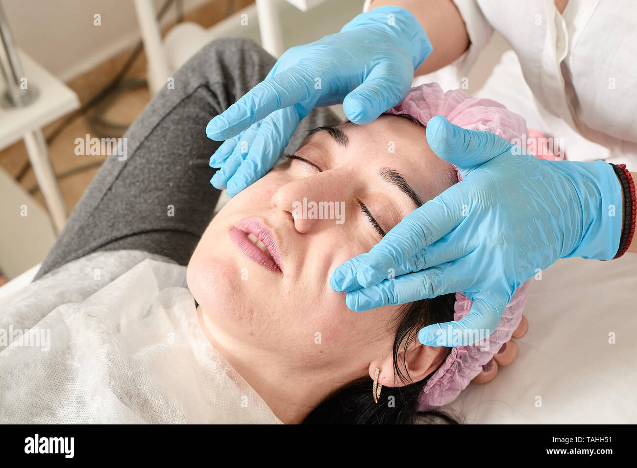 Jeune femme ne massage du visage professionnel après hydratation, adoucissement, régénérer, rajeunir, tonification des procédures cosmétiques dans le salon de beauté Banque D'Images