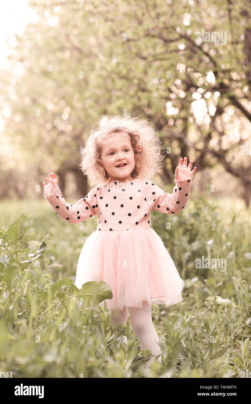 Sourire petite fille 4-5 ans élégant portant robe rose à l'extérieur.  L'enfance Photo Stock - Alamy
