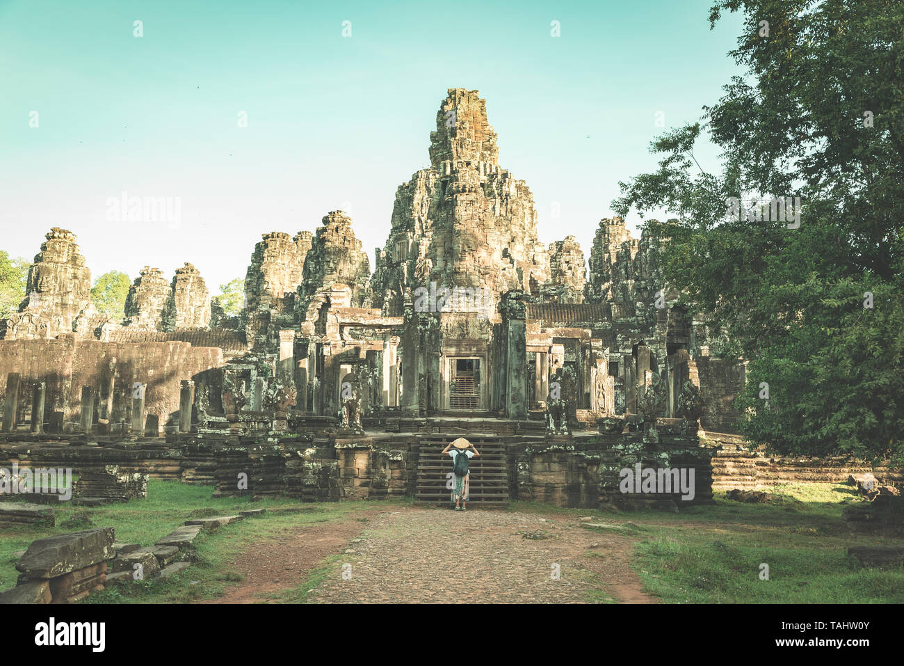 Femme au temple Bayon à la pierre à visages, Angkor Thom, lumière du matin, ciel bleu clair. Concept la méditation, célèbre destination de voyage, Banque D'Images