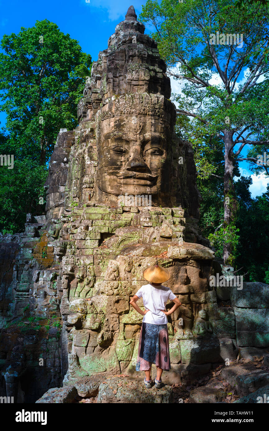Femme au temple Bayon à la pierre à visages, Angkor Thom, lumière du matin, ciel bleu clair. Concept la méditation, célèbre destination de voyage, Banque D'Images