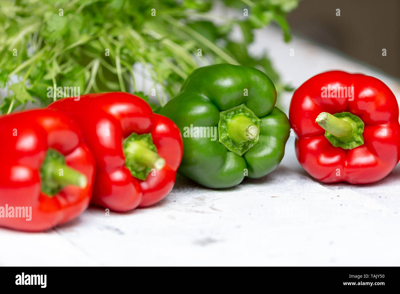 Trois poivrons rouges et verts, pepper​ doux avec de la coriandre en arrière-plan Banque D'Images