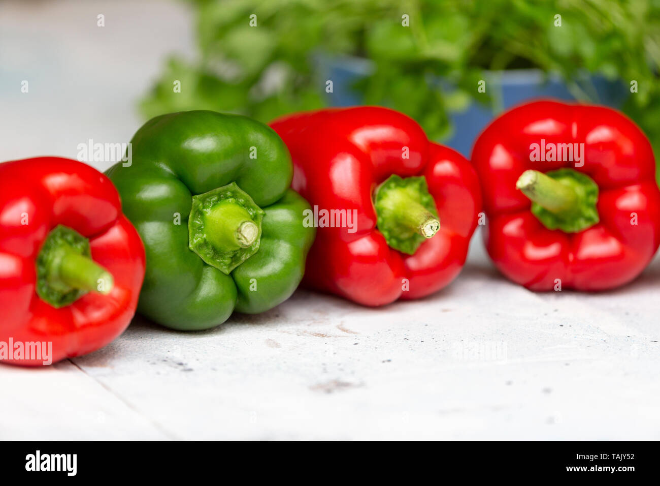 Trois poivrons rouges et verts, pepper​ doux avec de la coriandre en arrière-plan Banque D'Images