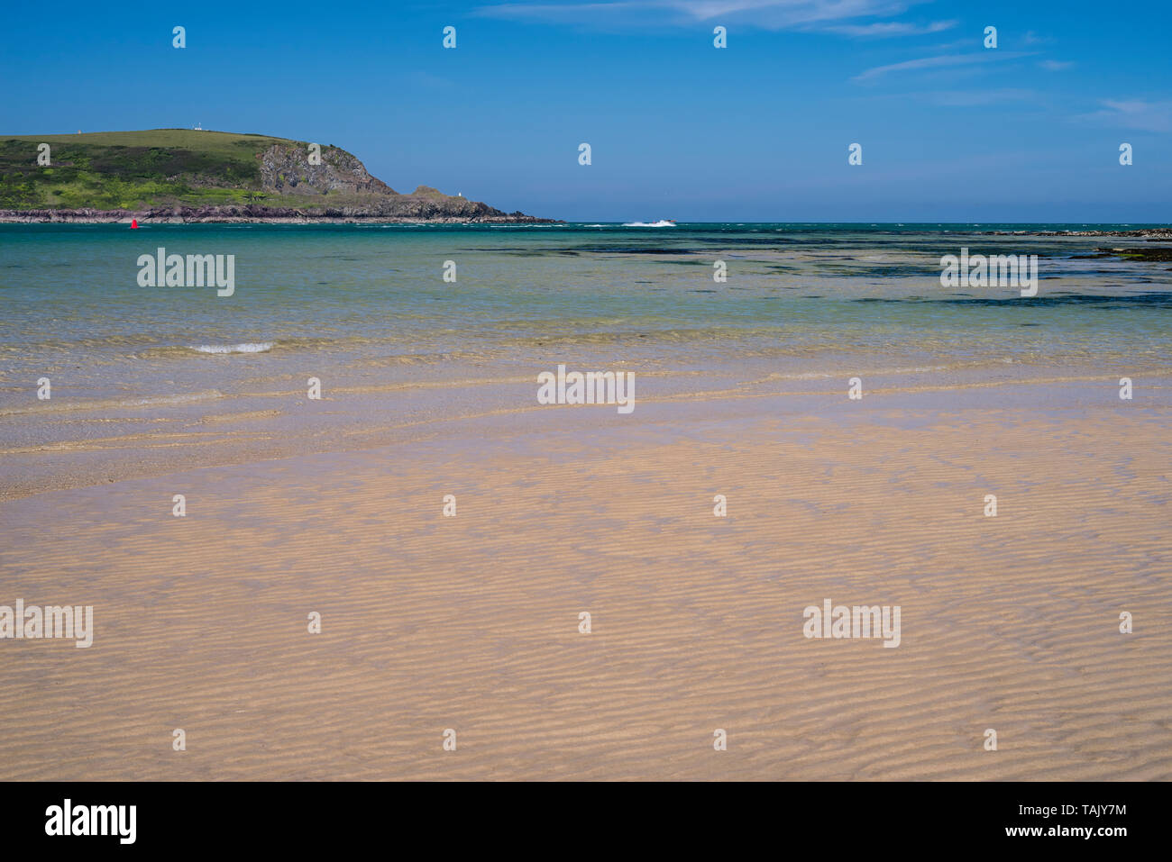 Une paisible journée ensoleillée à Daymer Bay, Trevetherick en Cornouailles du Nord, au Royaume-Uni avec des clapotis des vagues d'une plage de sable Banque D'Images