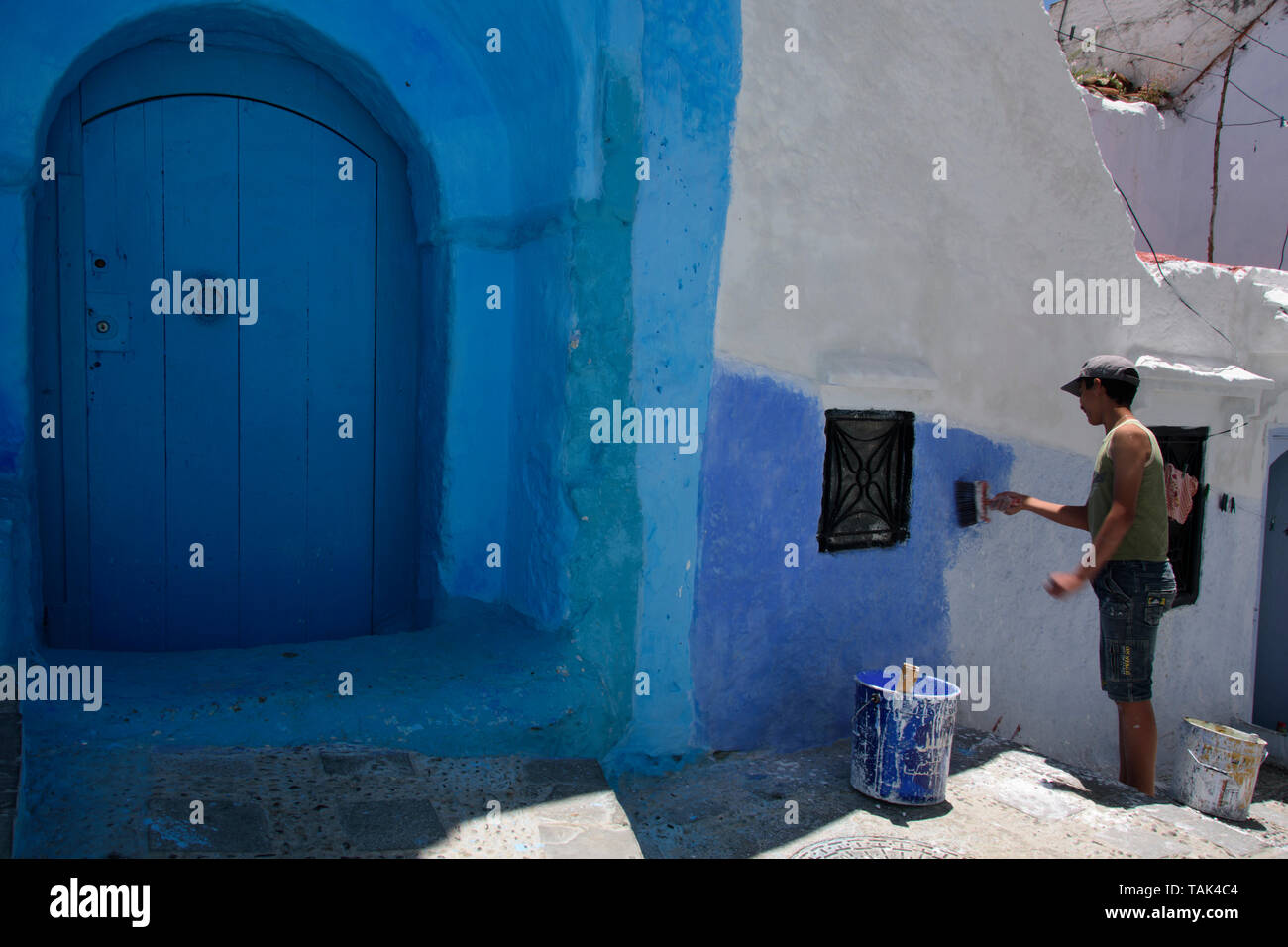 Chefchaouen, la ville bleue / the Blue Pearl au Maroc. Un homme peint son hous et wall blue Banque D'Images