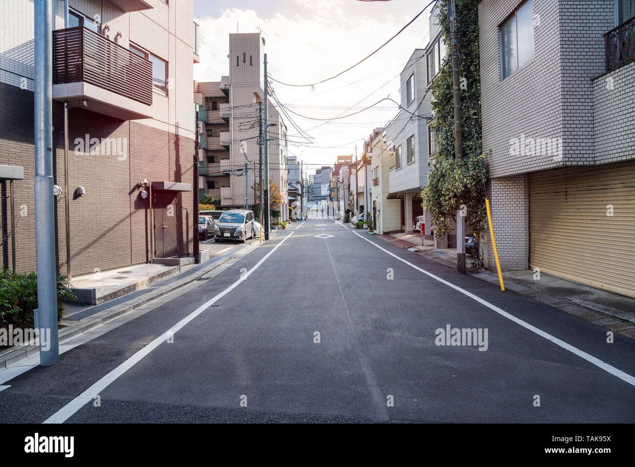 Rue étroite bordée d'immeubles d'appartements dans le centre de Tokyo sur un jour nuageux au début du printemps Banque D'Images