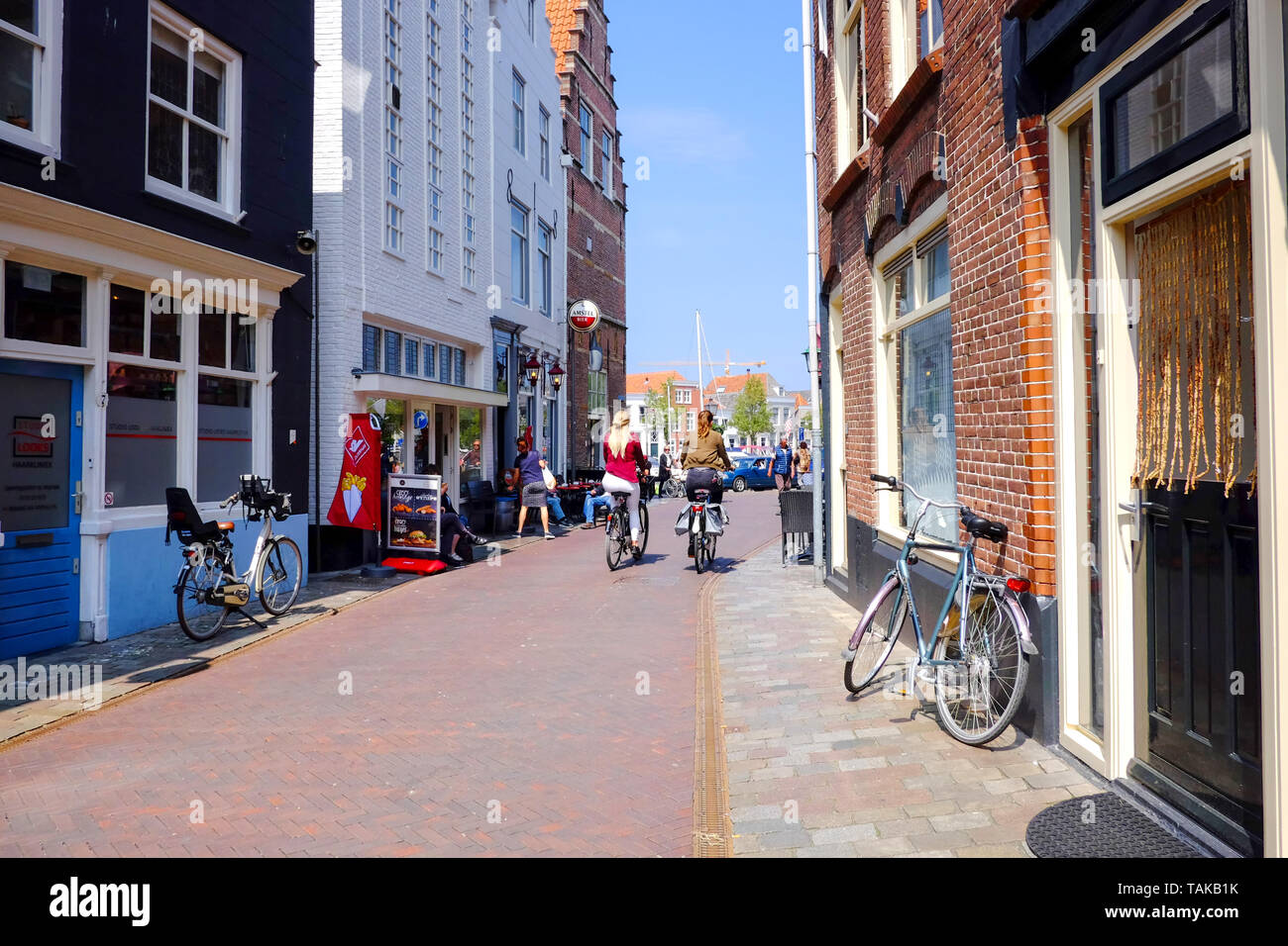Street view en néerlandais typique va, deux filles à vélo dans une vieille rue du 17ème siècle avec de vieux bâtiments et des vélos garés sur le bord de la route Banque D'Images