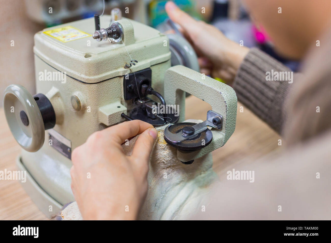 Professionnel hommes skinner, fourreur à l'aide de la machine à coudre spéciale pour coudre la peau de fourrure à l'atelier, atelier. La mode et le travail du cuir concept Banque D'Images