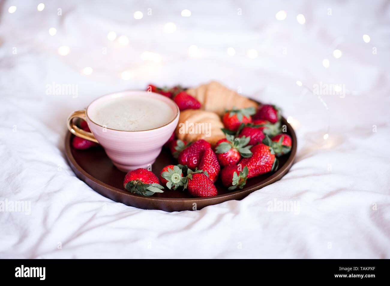 Tasse de café avec des fraises fraîches et des gâteaux dans le lit. Bonjour. Le petit-déjeuner. Banque D'Images
