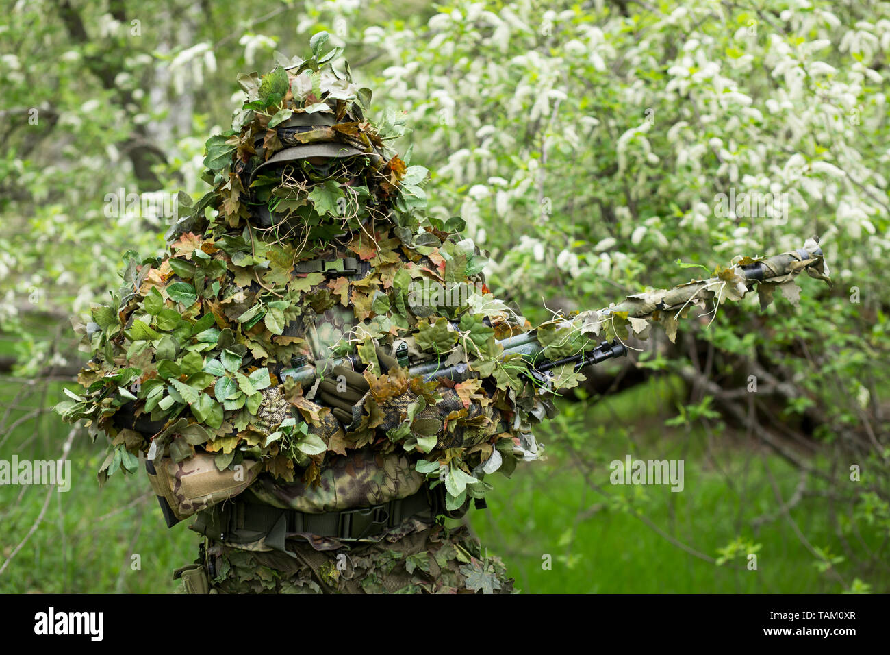 Closeup portrait d'un tireur d'hommes en tenue de camouflage militaire  armée verte vêtements avec une arme sur sa main sur l'arrière-plan d'arbres  en fleurs Photo Stock - Alamy