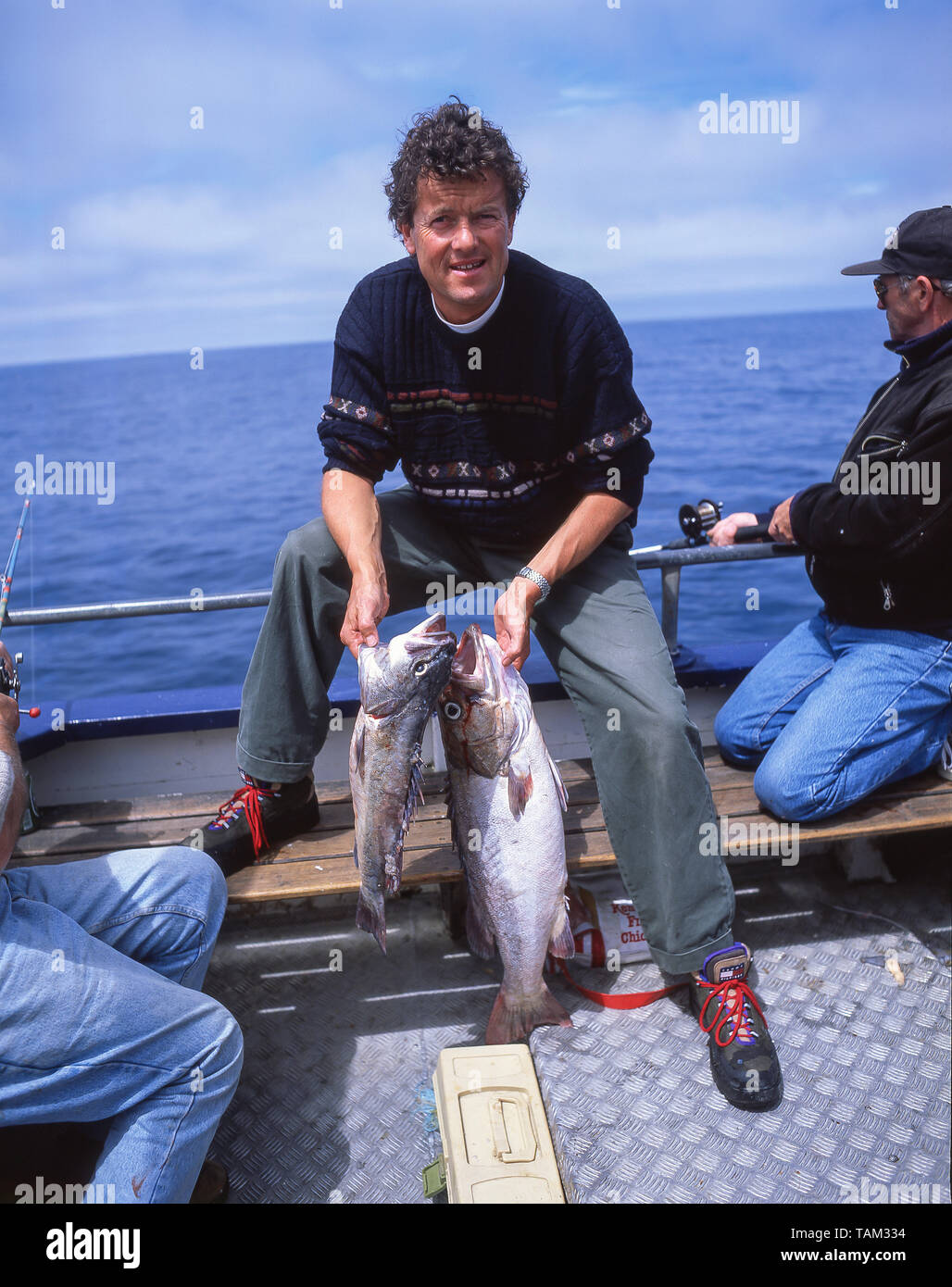 Jeune homme tenant un poisson attraper sur bateau de pêche, Oamaru, Région de l'Otago, île du Sud, Nouvelle-Zélande Banque D'Images