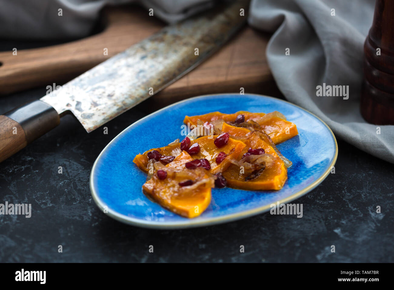 Citrouille grillés à la grenade, l'oignon et de miel. Citrouille cuite avec du vin blanc sur la table de la cuisine. Banque D'Images