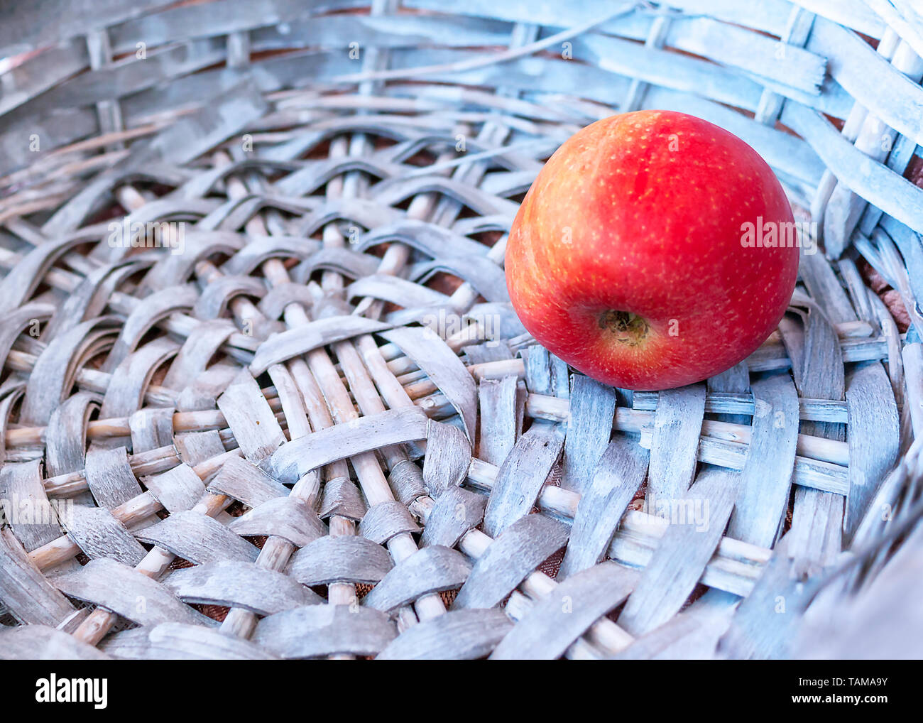 Seule pomme rouge dans un panier en osier gris. Copier l'espace. Banque D'Images