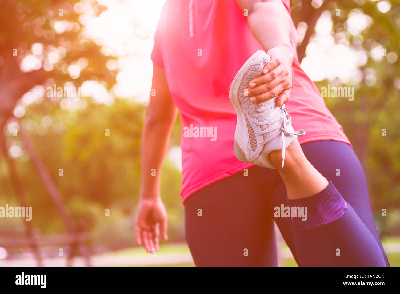 Stretching femme Sport la préparation musculaire des jambes pour courir dans le parc, piscine. Close up de la partie inférieure du corps de l'athlète féminine s'étire les jambes faire Banque D'Images