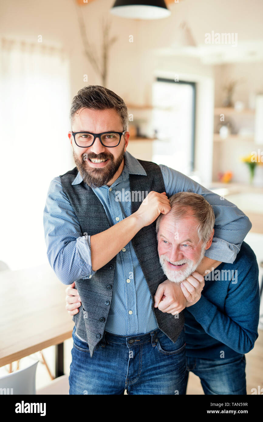Un adulte hipster fils et père des cadres supérieurs à l'intérieur à la maison, avoir du plaisir. Banque D'Images